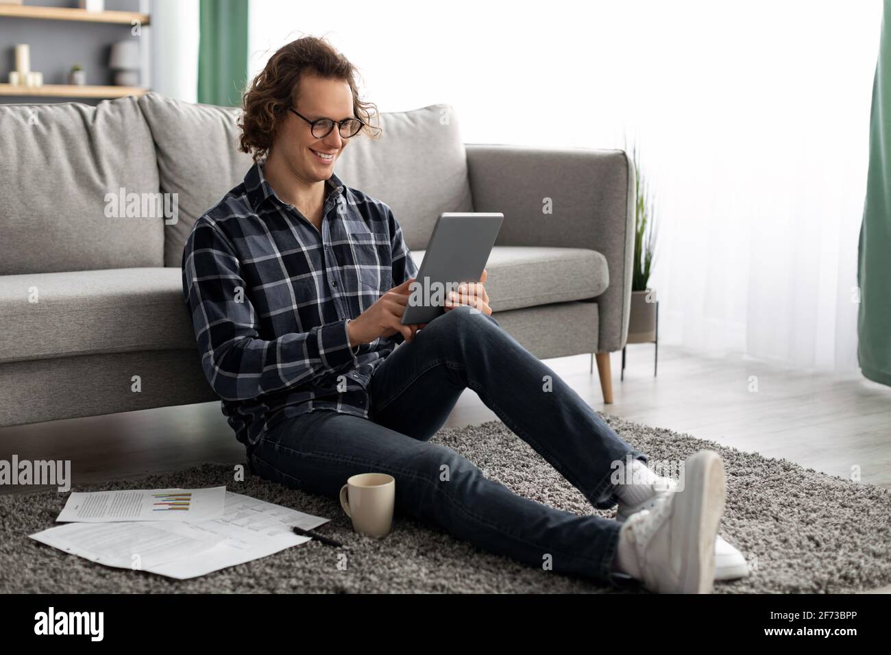 Cheerful Man Using Tablet Computer Browsing Internet Sitting At Home Stock Photo