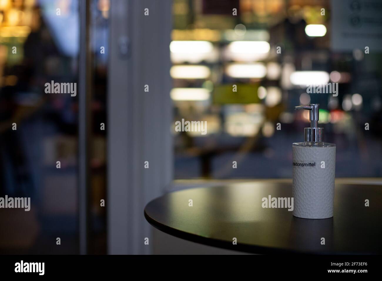 desinfection bottle on a table in front of a café during coronavirus lockdown in Germany with blurry background Stock Photo