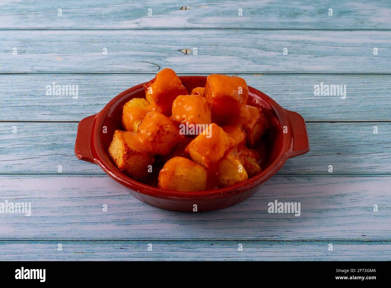 Spanish gastronomy concept. Clay plate with fried potatoes with spicy sauce called in Spain 'Patatas Bravas' Stock Photo