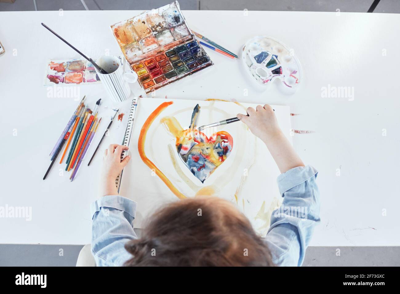 Cute little girl painting using watercolor paints. Top view of charming ...