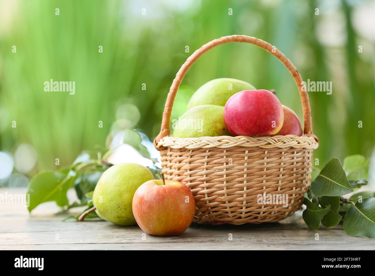 Basket with tasty apple and pear fruits on table outdoors Stock Photo
