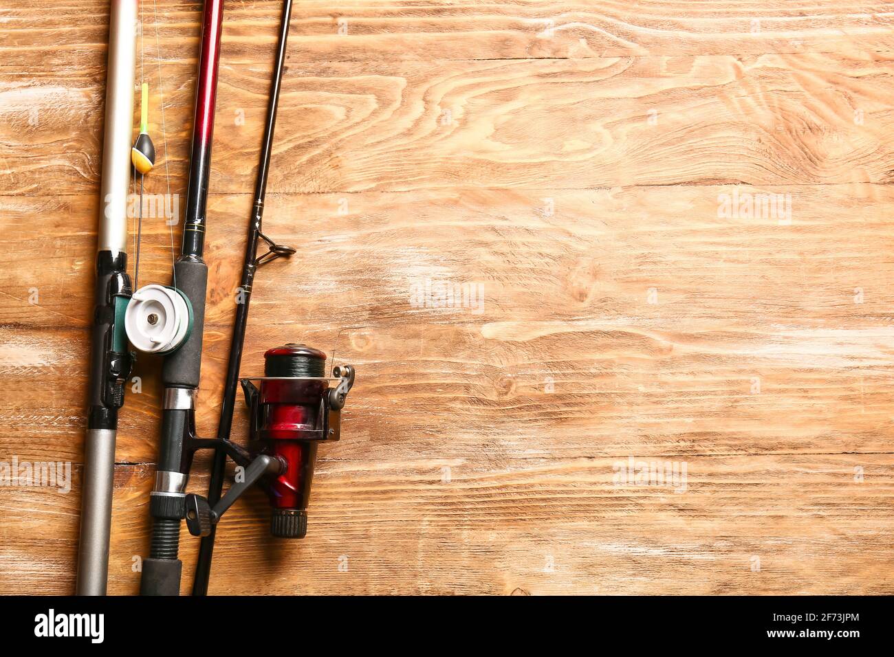 Different fishing rods on wooden background Stock Photo - Alamy