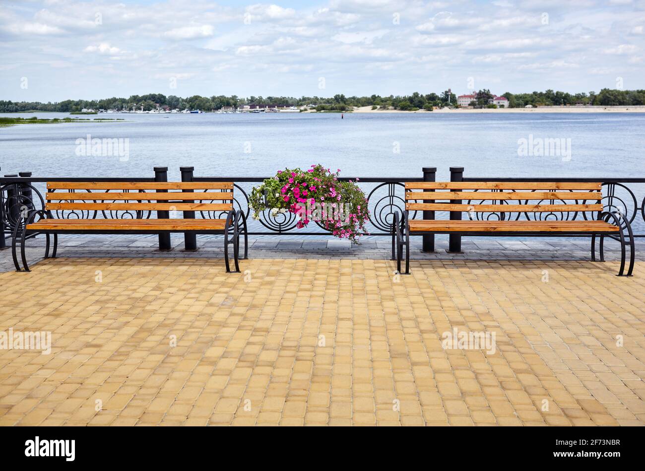 Embankment with benches with view on sea. Park wooden bench on the cobbled sidewalk Stock Photo