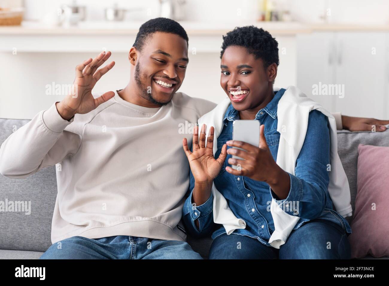 Black couple having videocall using smartphone waving hands Stock Photo