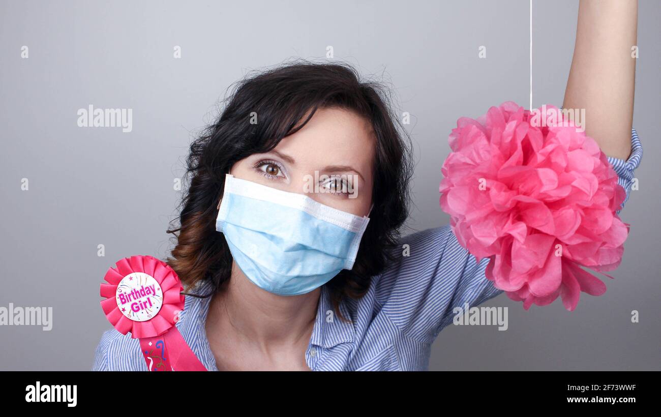 Woman wearing protection face mask against coronavirus. Woman in a mask with party supply. Birthday girl. Medical mask, Close up shot, Select focus, P Stock Photo