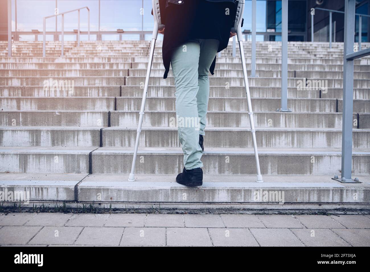 Man on crutches climbs a big set of stairs Stock Photo Alamy