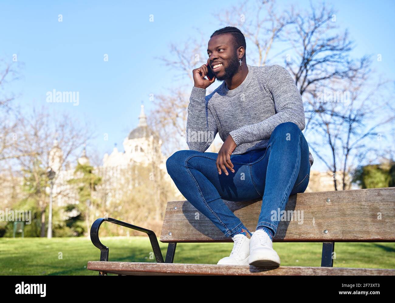 Happy black man talking on smart phone sitting in a park on a sunny day. High quality photo Stock Photo