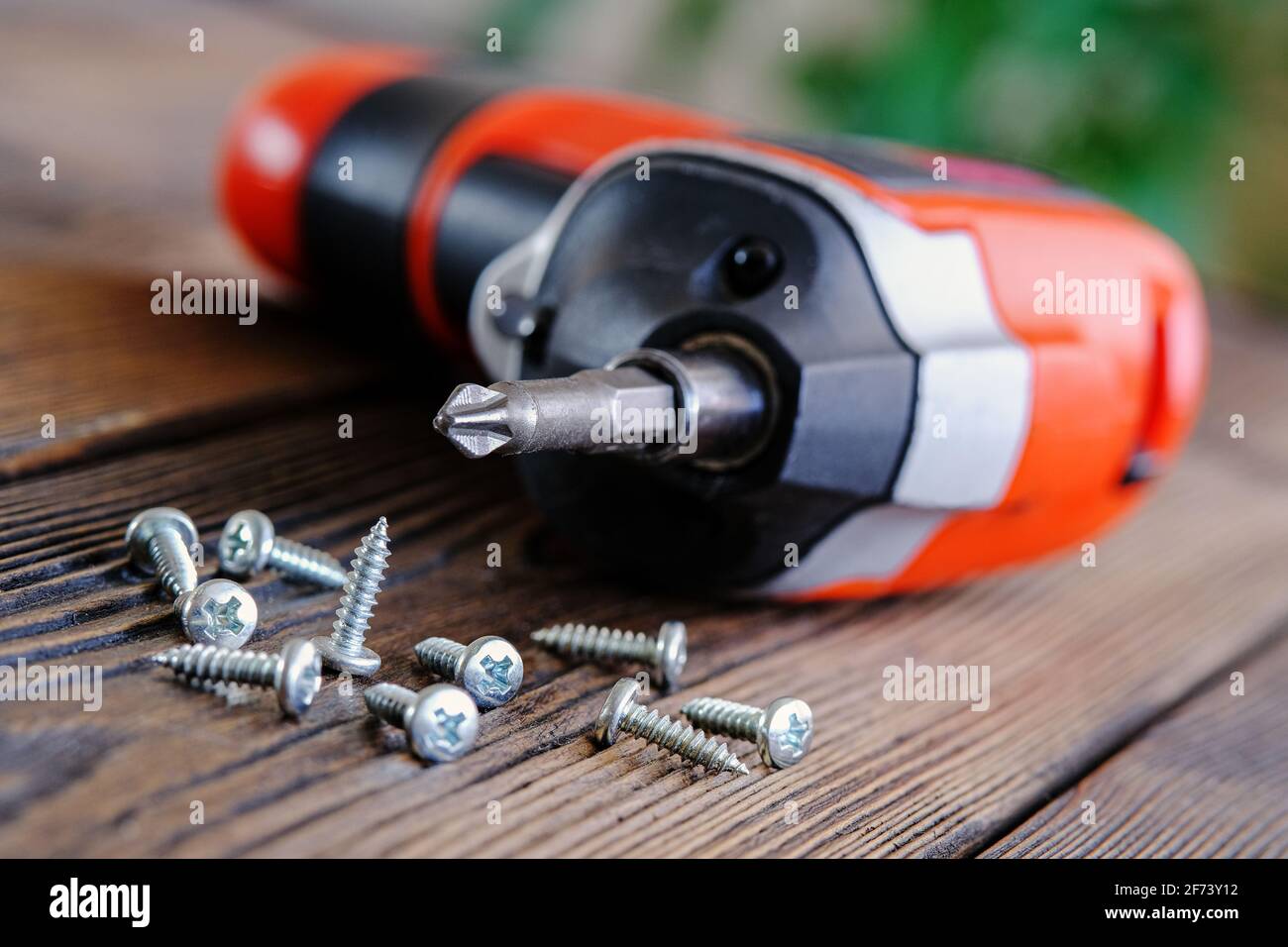 Home repair of kitchen furniture. Twisting a loose self-tapping screw with an electric screwdriver Stock Photo