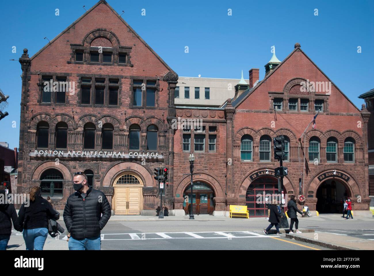 People in masks are walking in a front of the historical building. Stock Photo