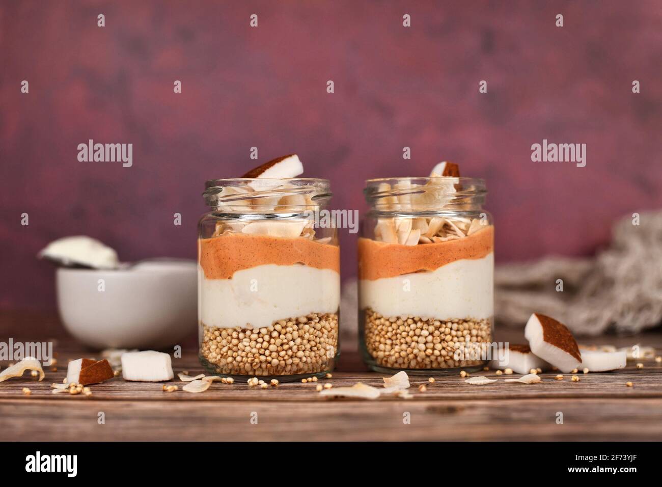 Healthy layered breakfast or dessert with puffed quinoa grains, yogurt and coconut flakes and pieces in glass Stock Photo