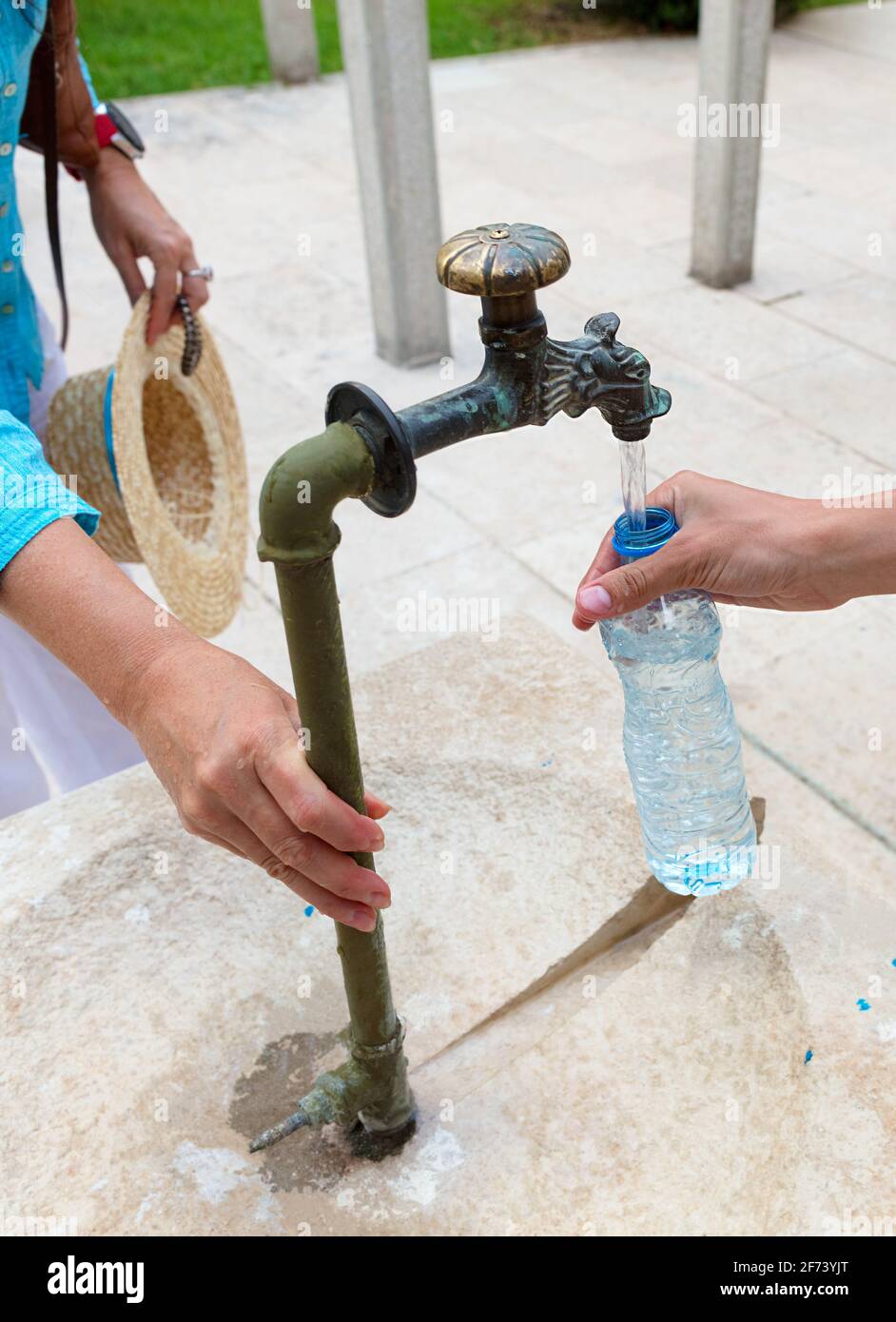 People on a walk collect drinking clean clear water from an old source into a plastic bottle. Stock Photo