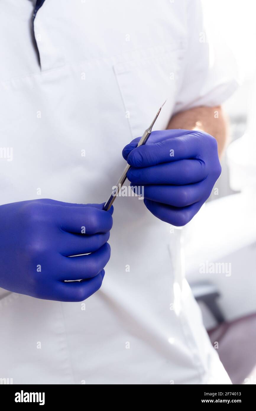 Male hands in blue medical gloves hold a dental instrument Stock Photo ...