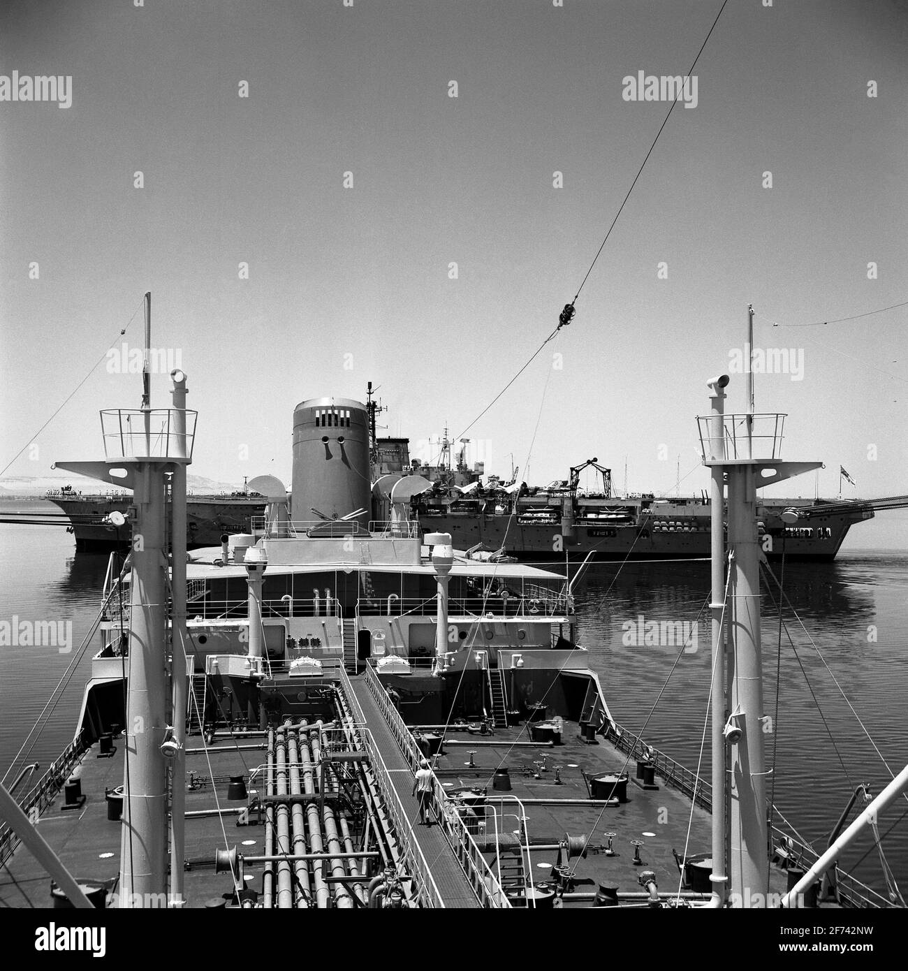 AJAXNETPHOTO. 1965. GREAT BITTER LAKE, EGYPT - ARK EAST OF SUEZ - HMS ARK ROYAL PASSING THROUGH THE GREAT BITTER LAKE OF THE SUEZ CANAL ON PASSAGE TO THE FAR EAST ASTERN OF THE GULF OIL TANKER CEUTA AWAITING PASSAGE NORTHBOUND.  PHOTO:JONATHAN EASTLAND/AJAX REF:657 13 2 Stock Photo