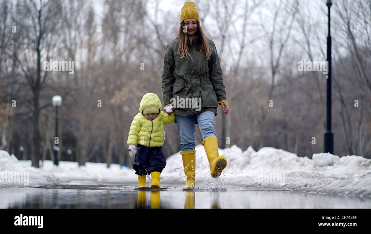 Mom and daughter walking in a puddle in yellow rubber boots Stock Photo ...