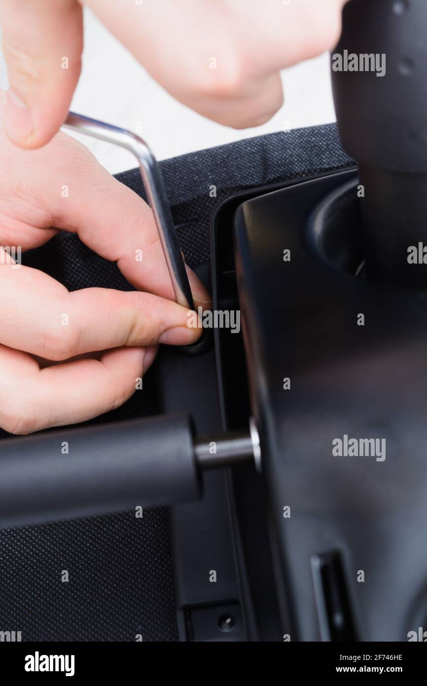 Caucasian man hands screw chair lifting mechanism. Assembling office