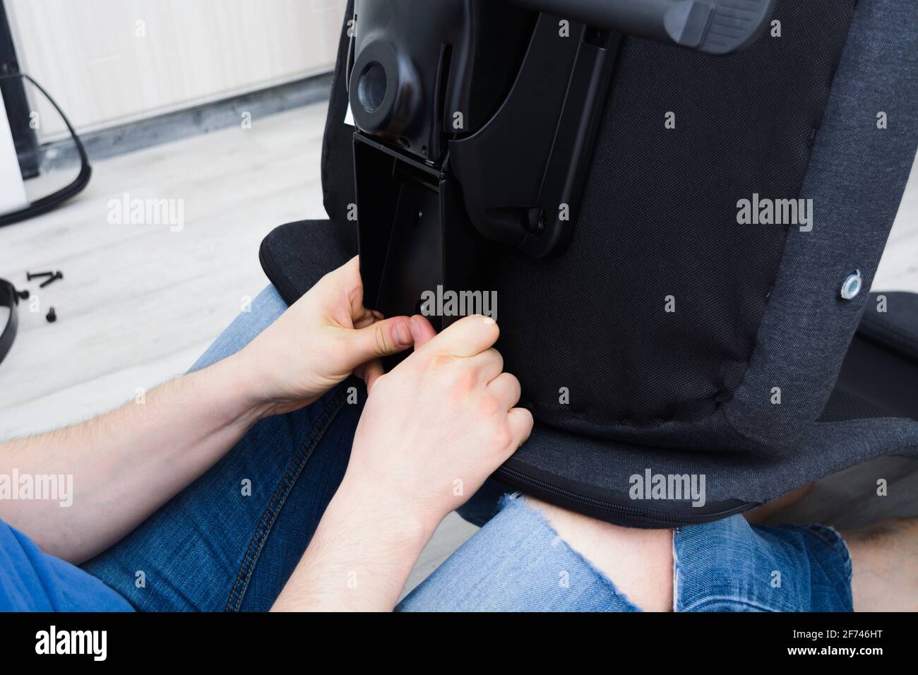 Caucasian man hands screw chair lifting mechanism. Assembling office chair Stock Photo