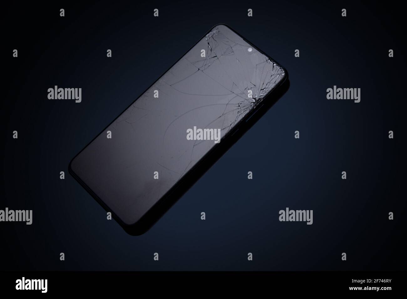 Modern touchscreen smartphone with broken screen on dark background Stock Photo
