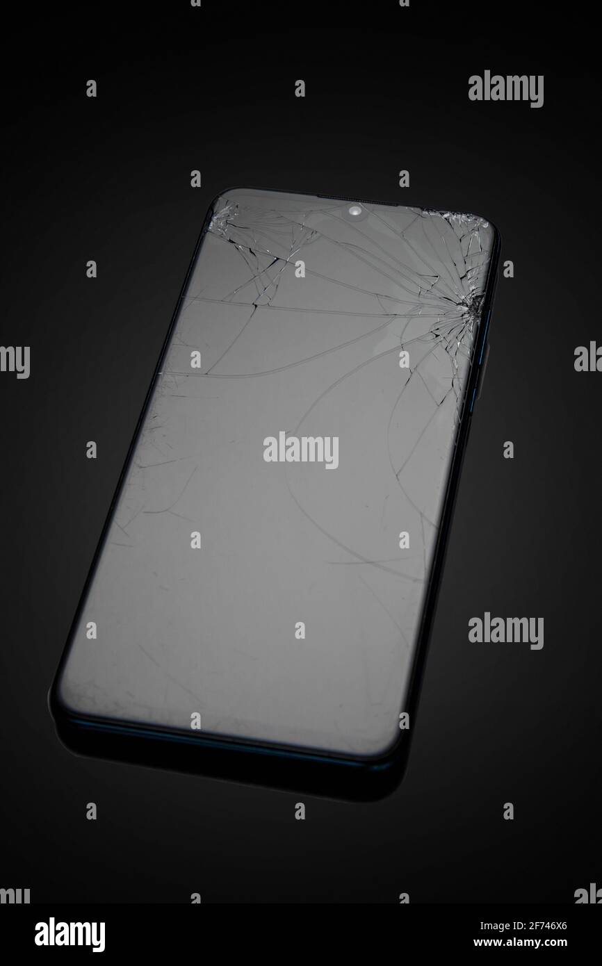 Modern touchscreen smartphone with broken screen on dark background Stock Photo