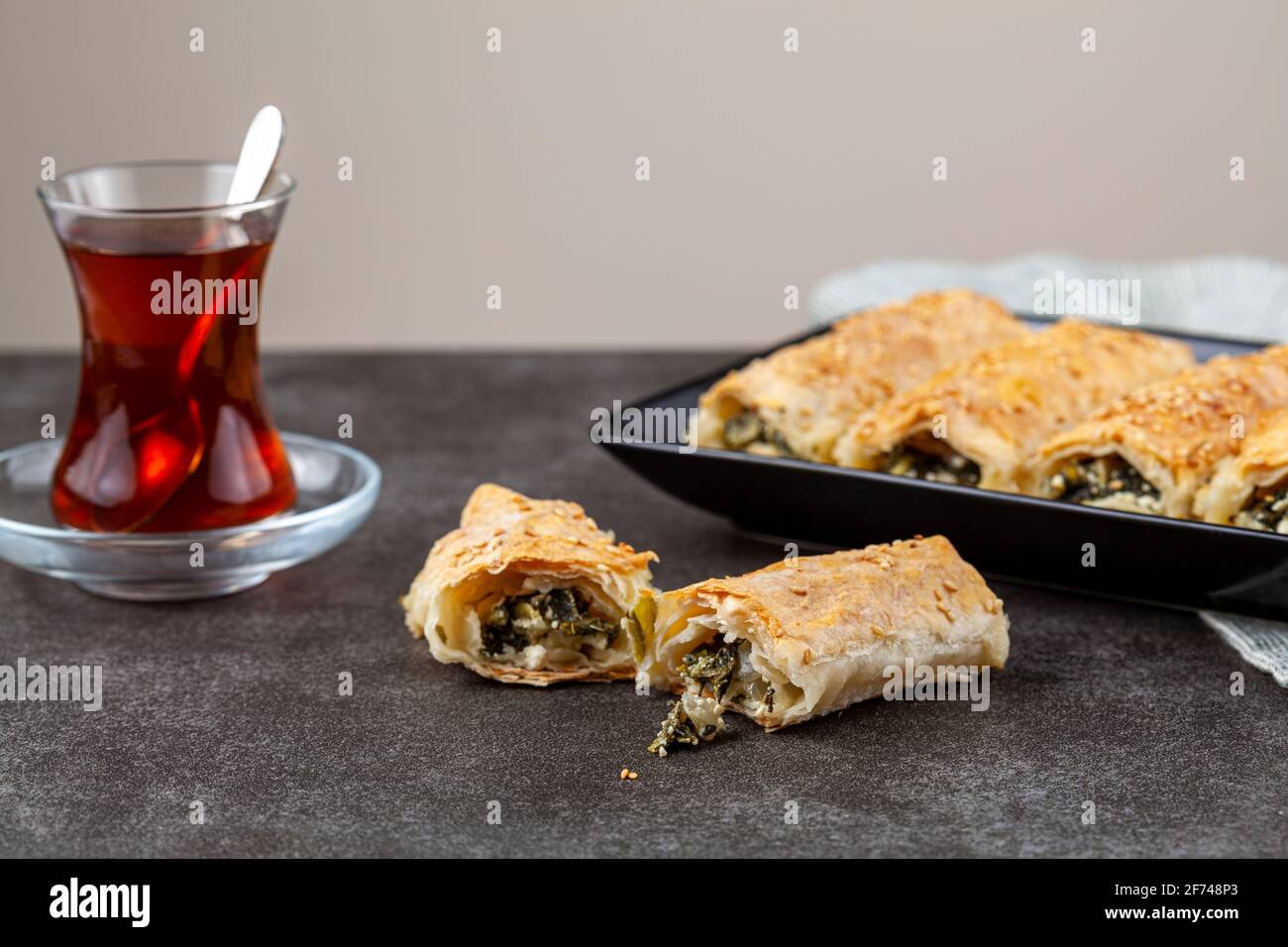 Traditional Turkish spinach pastry rolls ( Ispanakli borek ) served on a porcelain plate. Homemade recipe made using spinach and cheese fillings insid Stock Photo