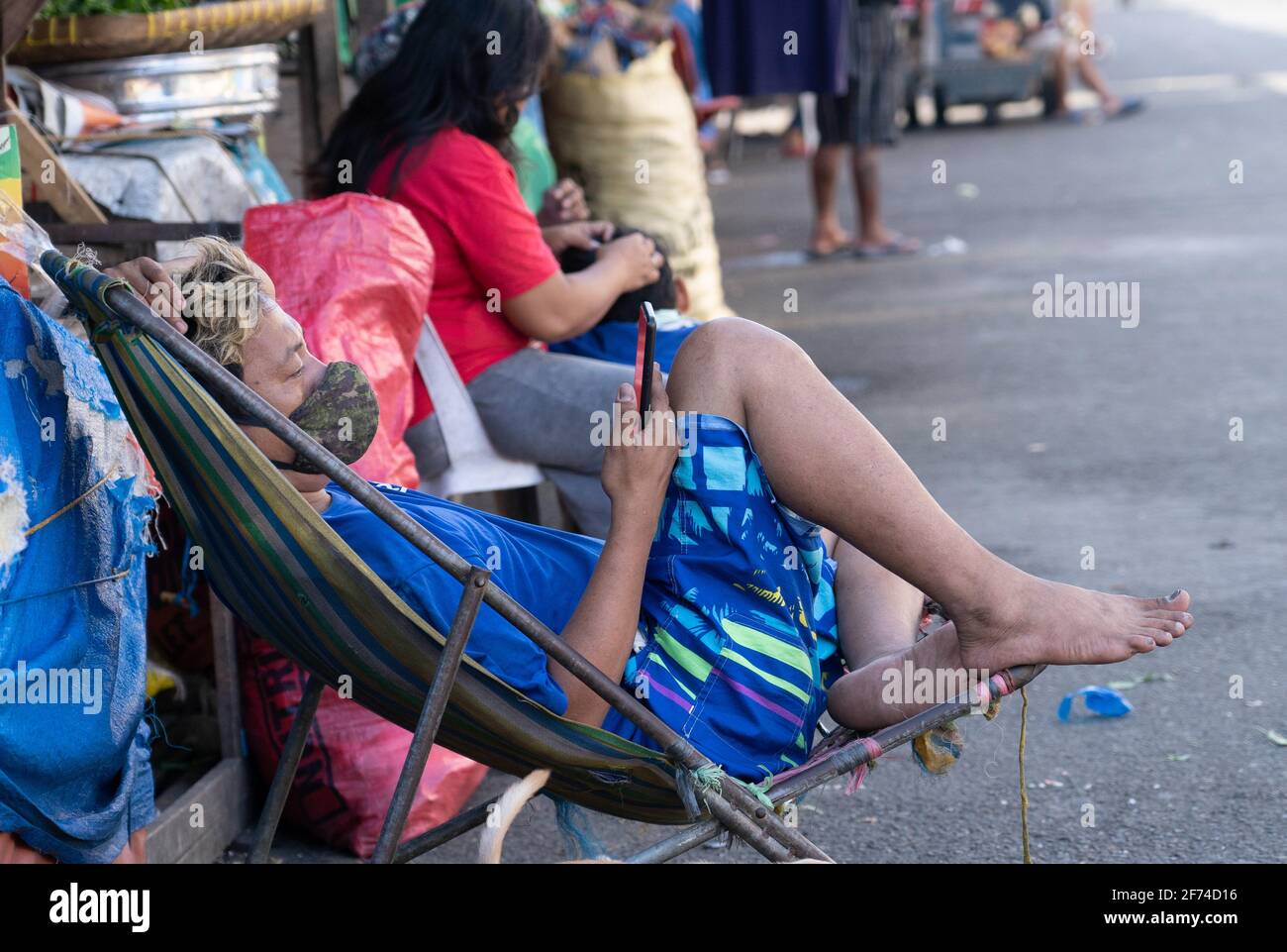 A man sitting in a chair using a mobile phone, Carbon Market, Cebu City, Philippines Stock Photo