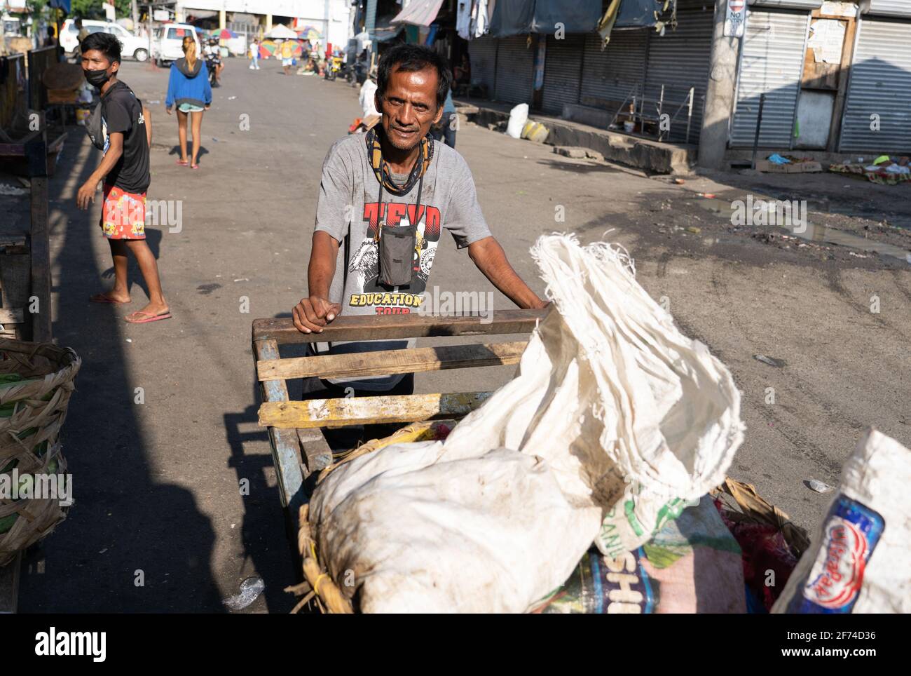 A Filipino man pushing a cart through a market area of Cebu City, Philippines Stock Photo