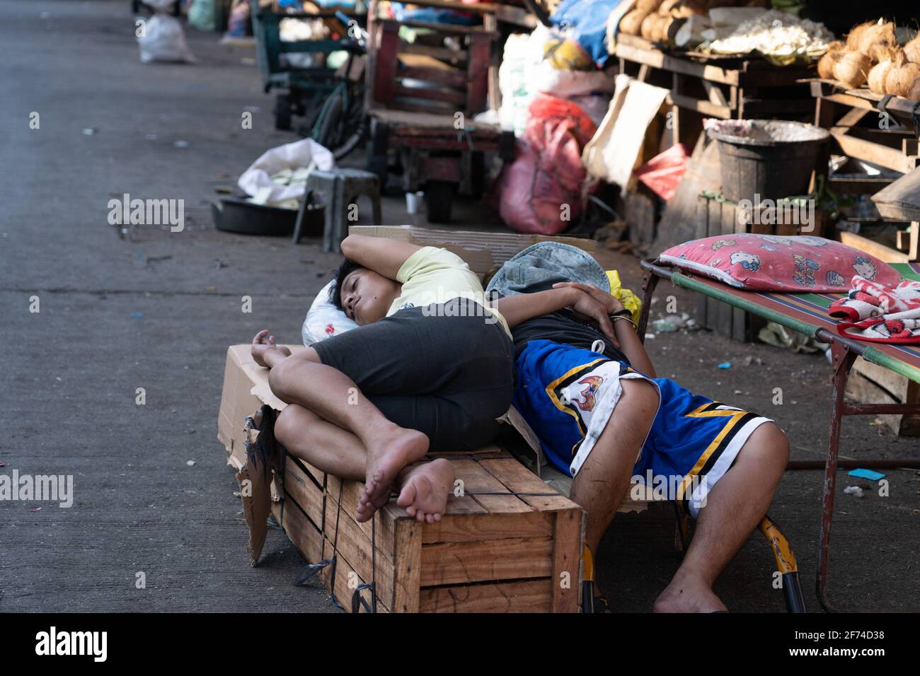 Young teenagers sleep on boxes in a market area of Cebu City, Philippines Stock Photo