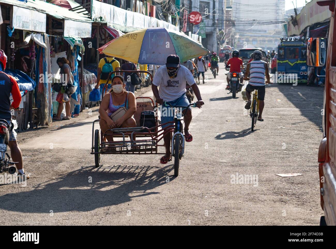 A woman being transported in a tricycle through a market area of Cebu City, Philippines Stock Photo