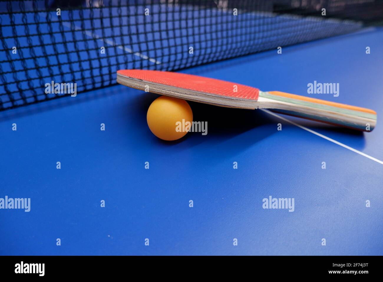 on the tennis table is a ball and two table tennis rackets Stock Photo