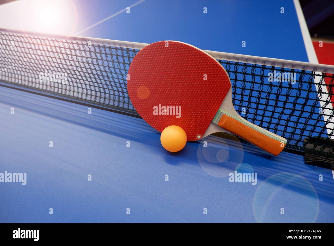 on the tennis table is a ball and two table tennis rackets Stock Photo