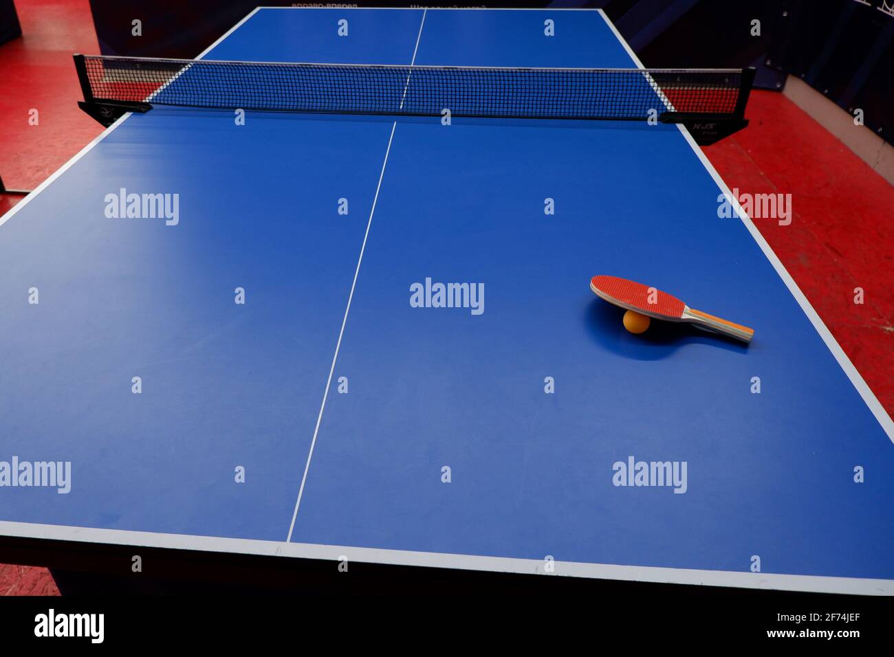 on the tennis table is a ball and two table tennis rackets Stock Photo
