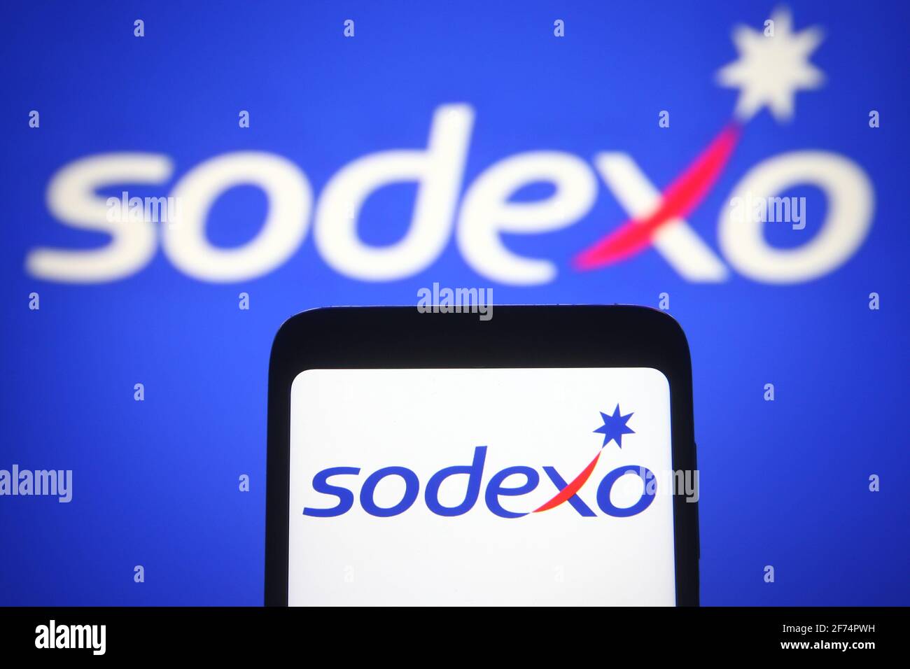 In this photo illustration the Sodexo logo of a French food services and facilities management company is seen on a smartphone and a pc screen. Stock Photo