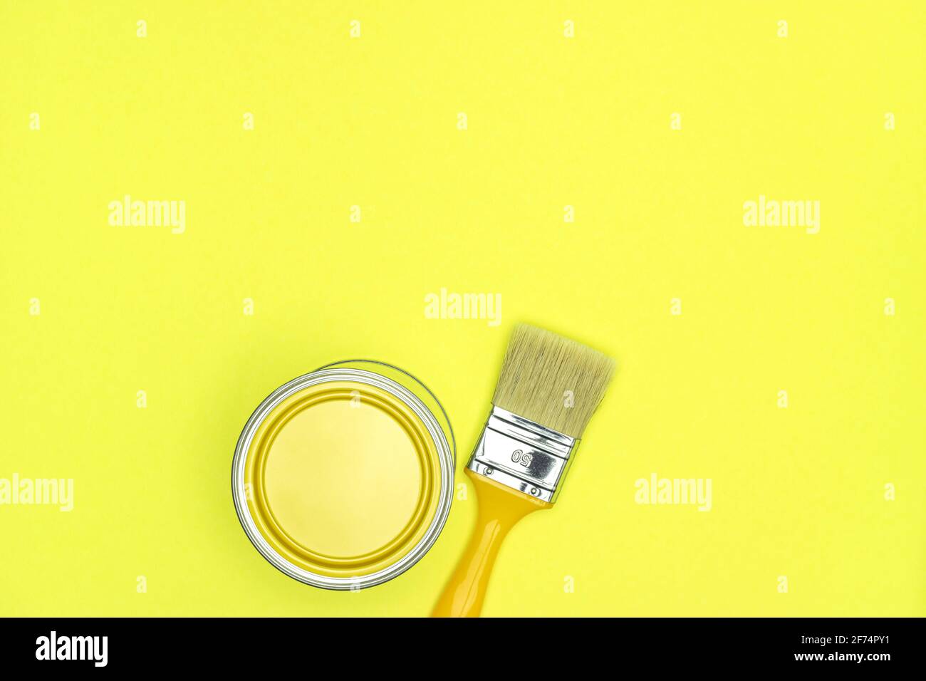 yellow paint can with paintbrush on illuminating yellow background. top view, copy space Stock Photo