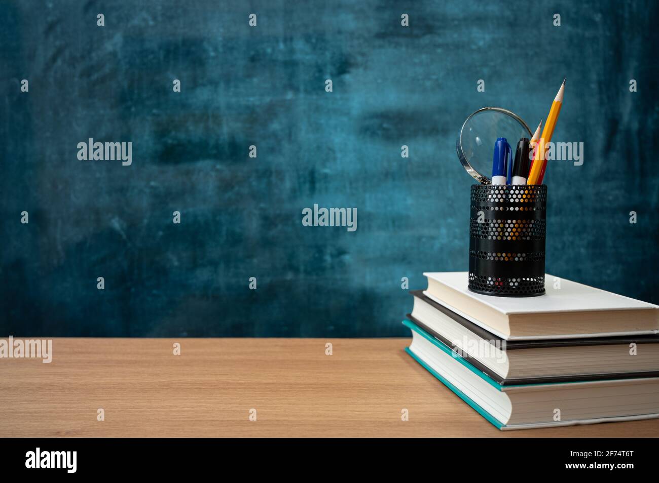 Books on the desk and a blank blackboard. Education concept. Stock Photo