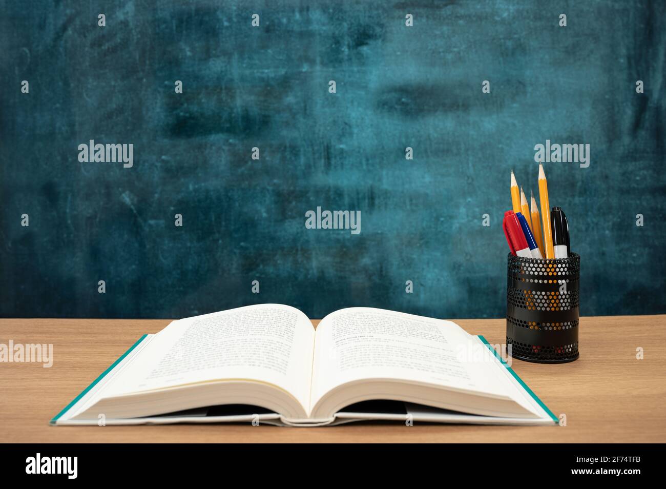 Books on the desk and a blank blackboard. Education concept. Stock Photo