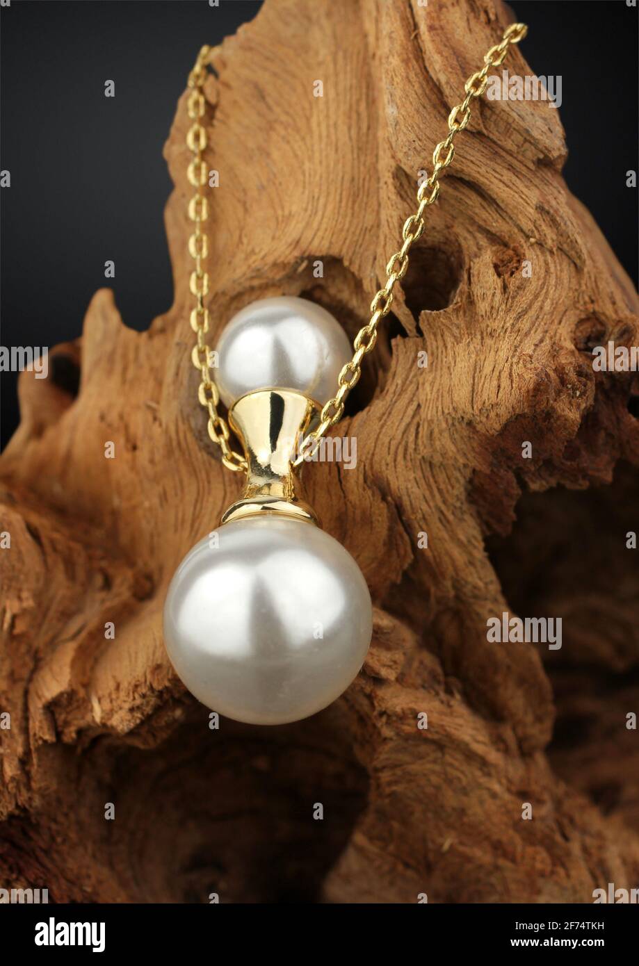 golden jewelry pendant with pearl on dark wood background, soft focus Stock Photo