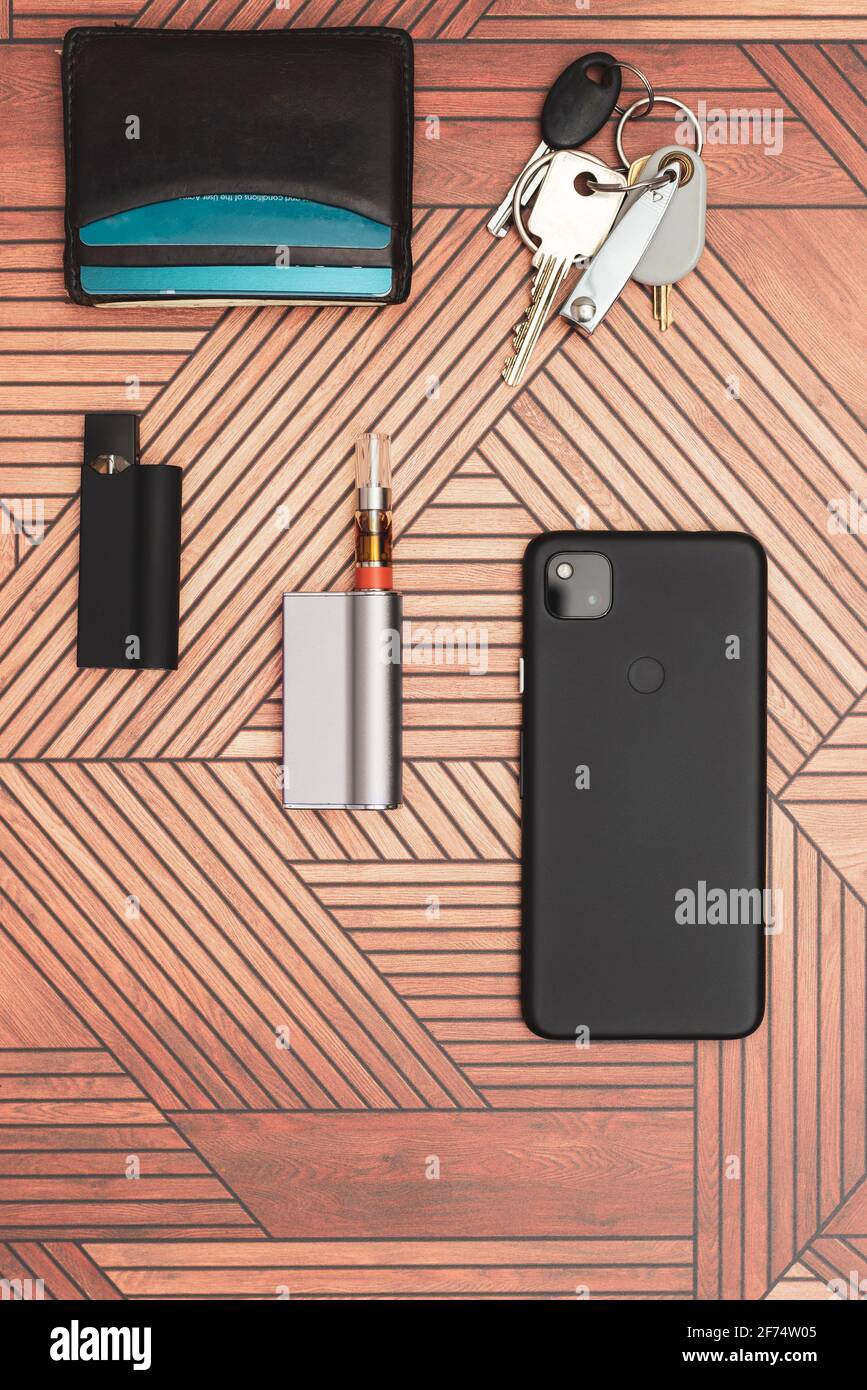 An every day carry flat lay with a cannabis vape cartridge and electronic cigarette. Stock Photo