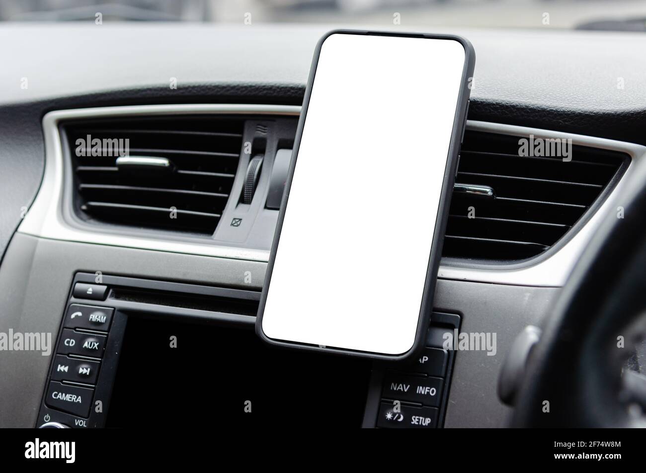 Mobile phone on the car air vent.Blank with white screen.Mock up smart phone in car. Stock Photo