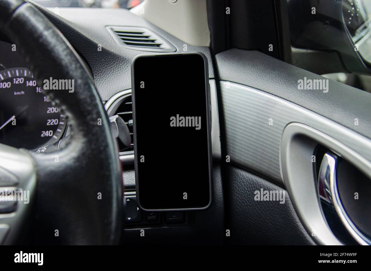 Mobile phone on the car air vent.Blank with white screen.Mock up smart phone in car. Stock Photo