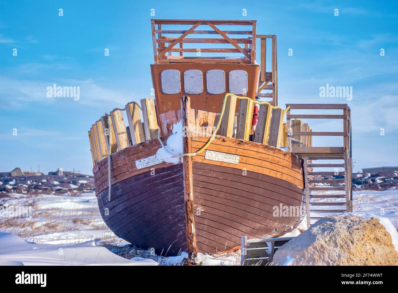 An old wooden boat on display out of the water and in the snow, in a public park in Churchill, Manitoba, Canada. Stock Photo