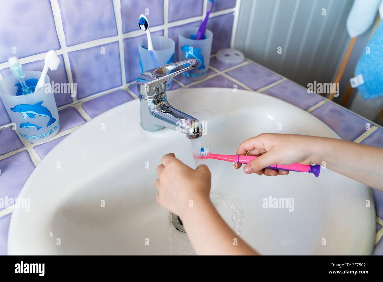 From above anonymous girl washing the toothbrush in the bathroom Stock