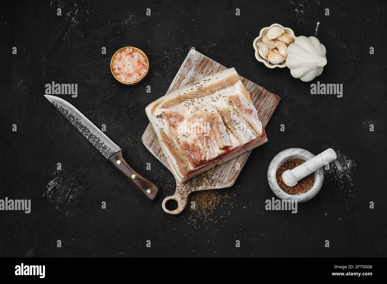 Overhead view of salted with caraway pork belly lard on cutting board