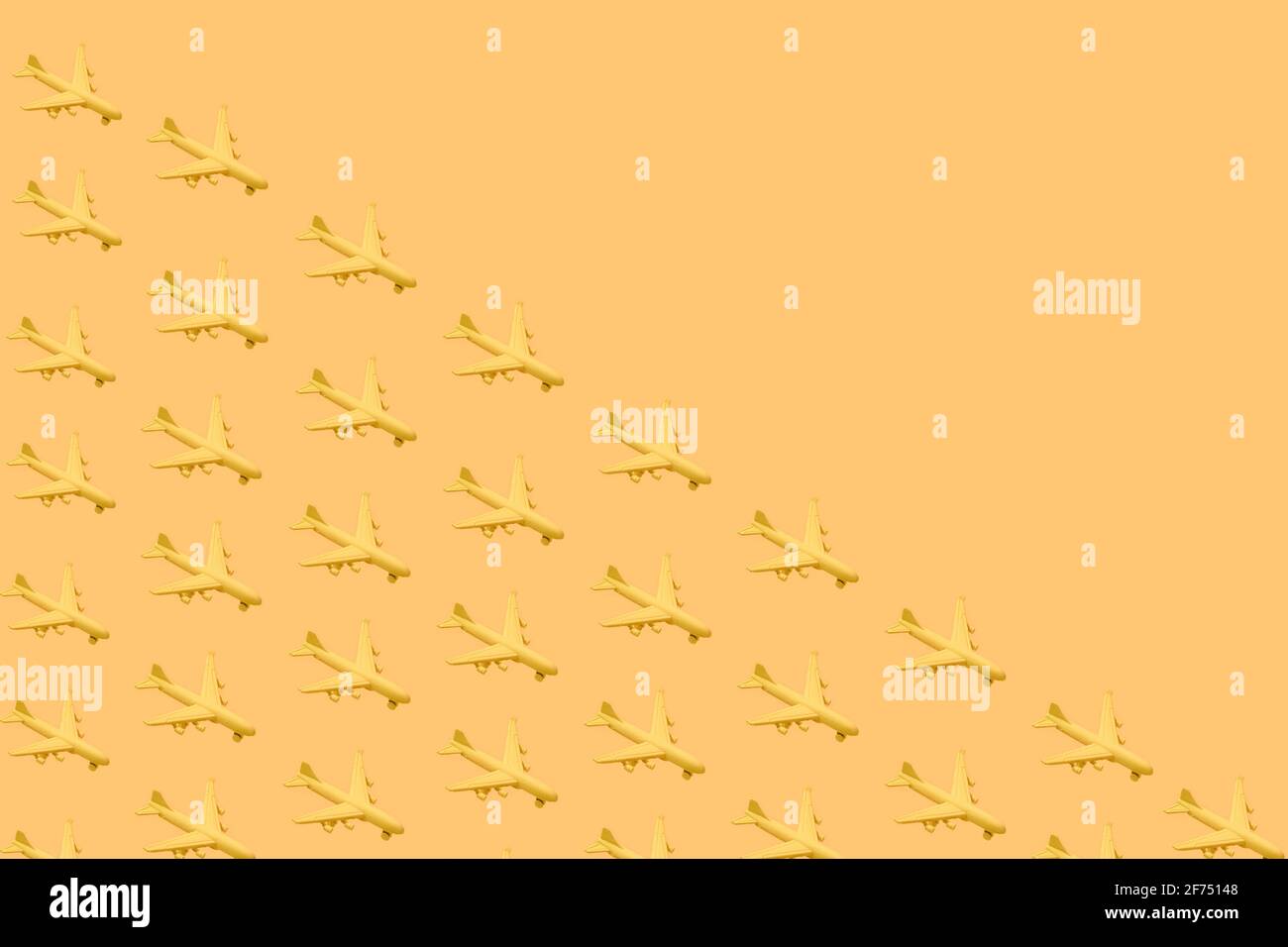 From above of composition of many little yellow airplanes placed against yellow background in studio Stock Photo