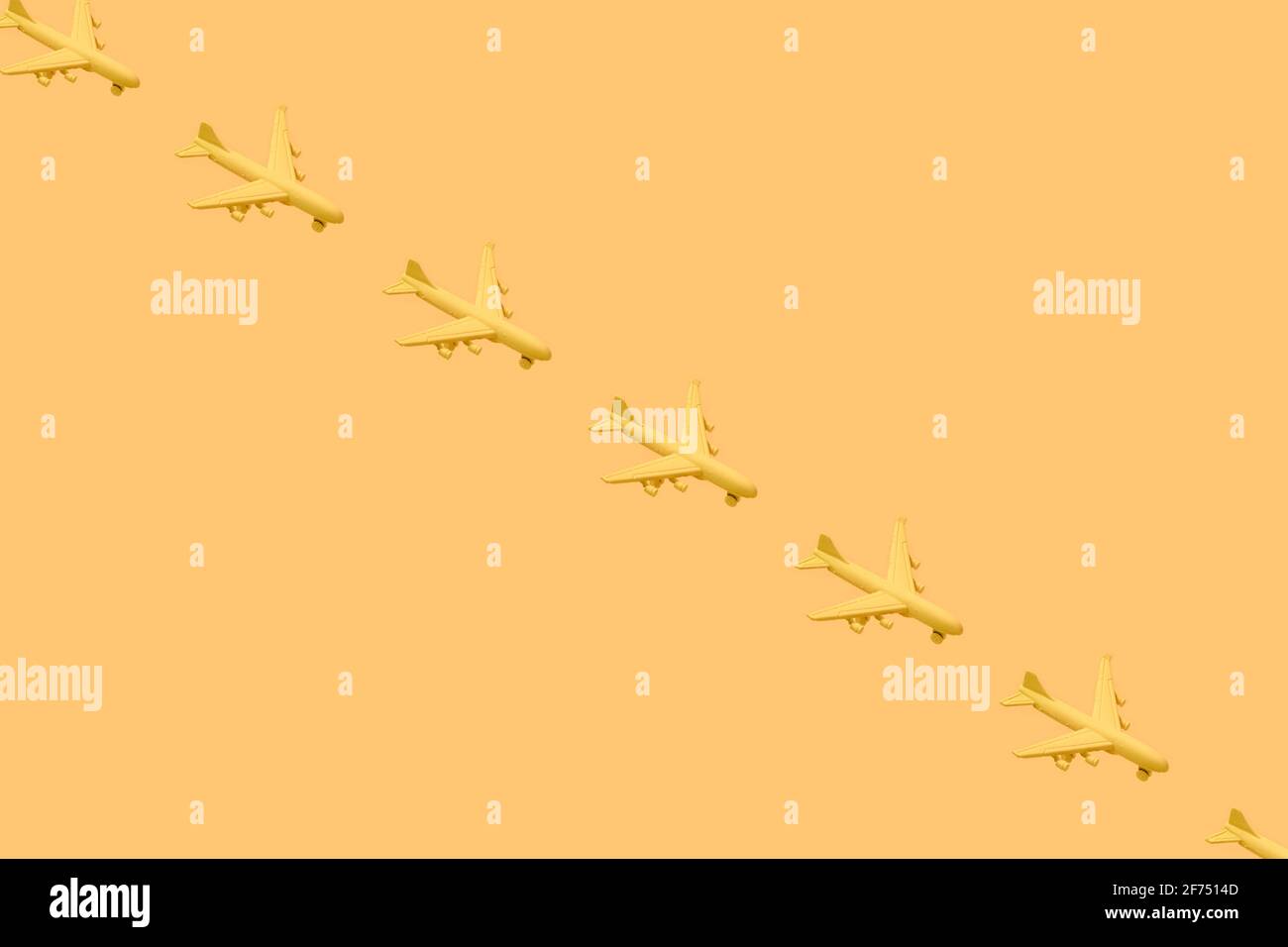From above of composition of many little yellow airplanes placed against yellow background in studio Stock Photo