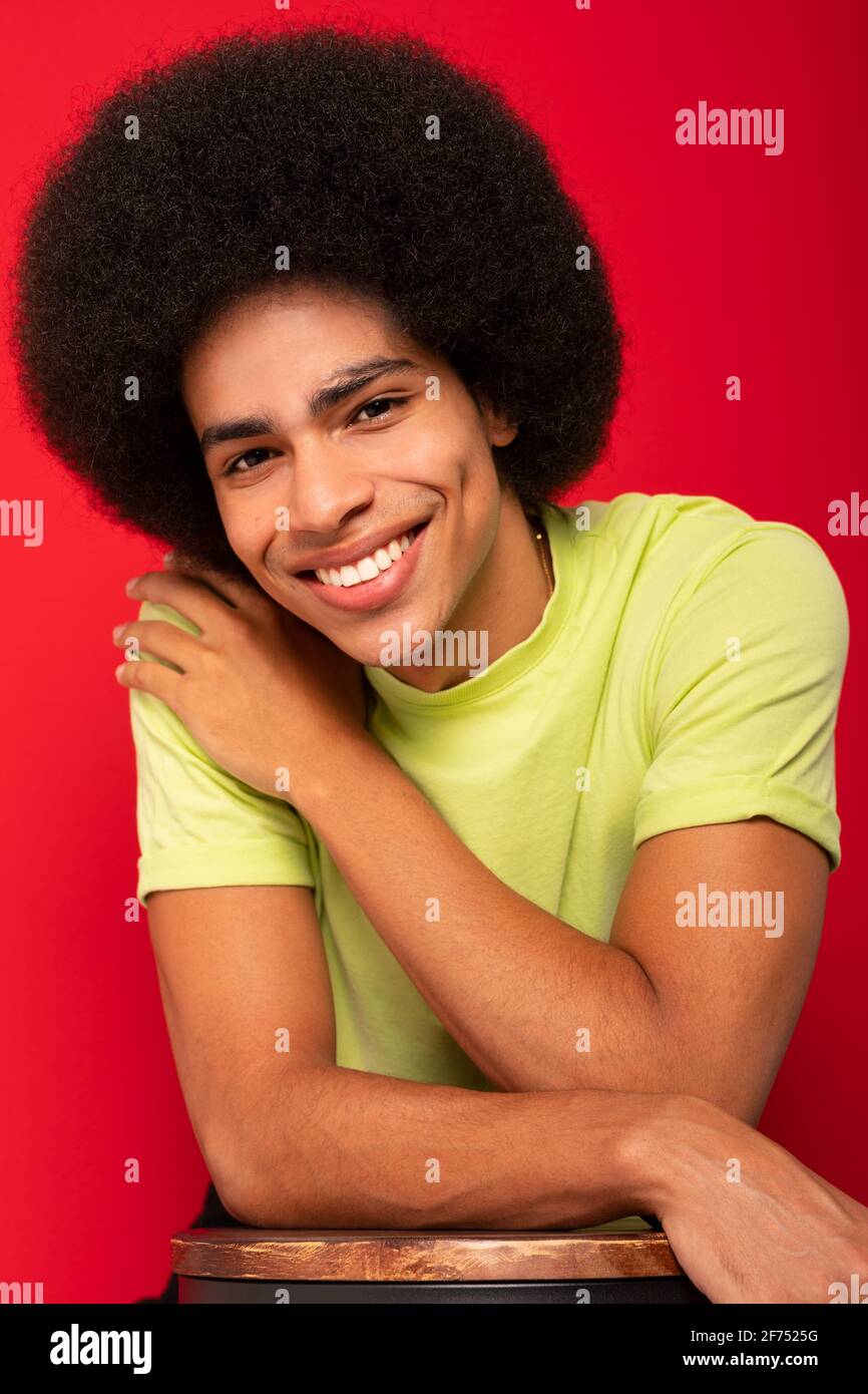 Young self cheerful African American male in casual t shirt looking at camera on red background Stock Photo
