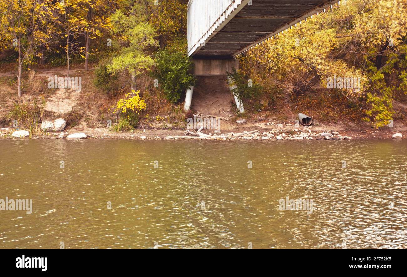 A bridge surrounded by autumn foliage over a river in Toronto, Ontario under an overcast sky. Stock Photo