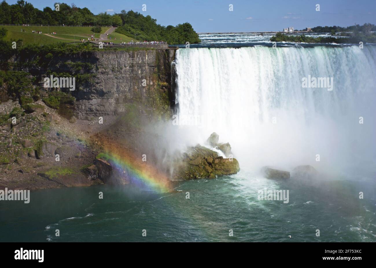A rainbow shines bright at Niagara Falls during the day. Stock Photo