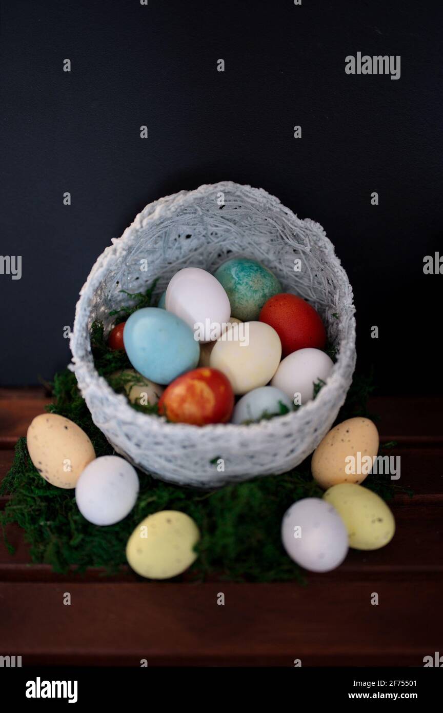 Colorful Easter eggs in wicker basket on black background Stock Photo