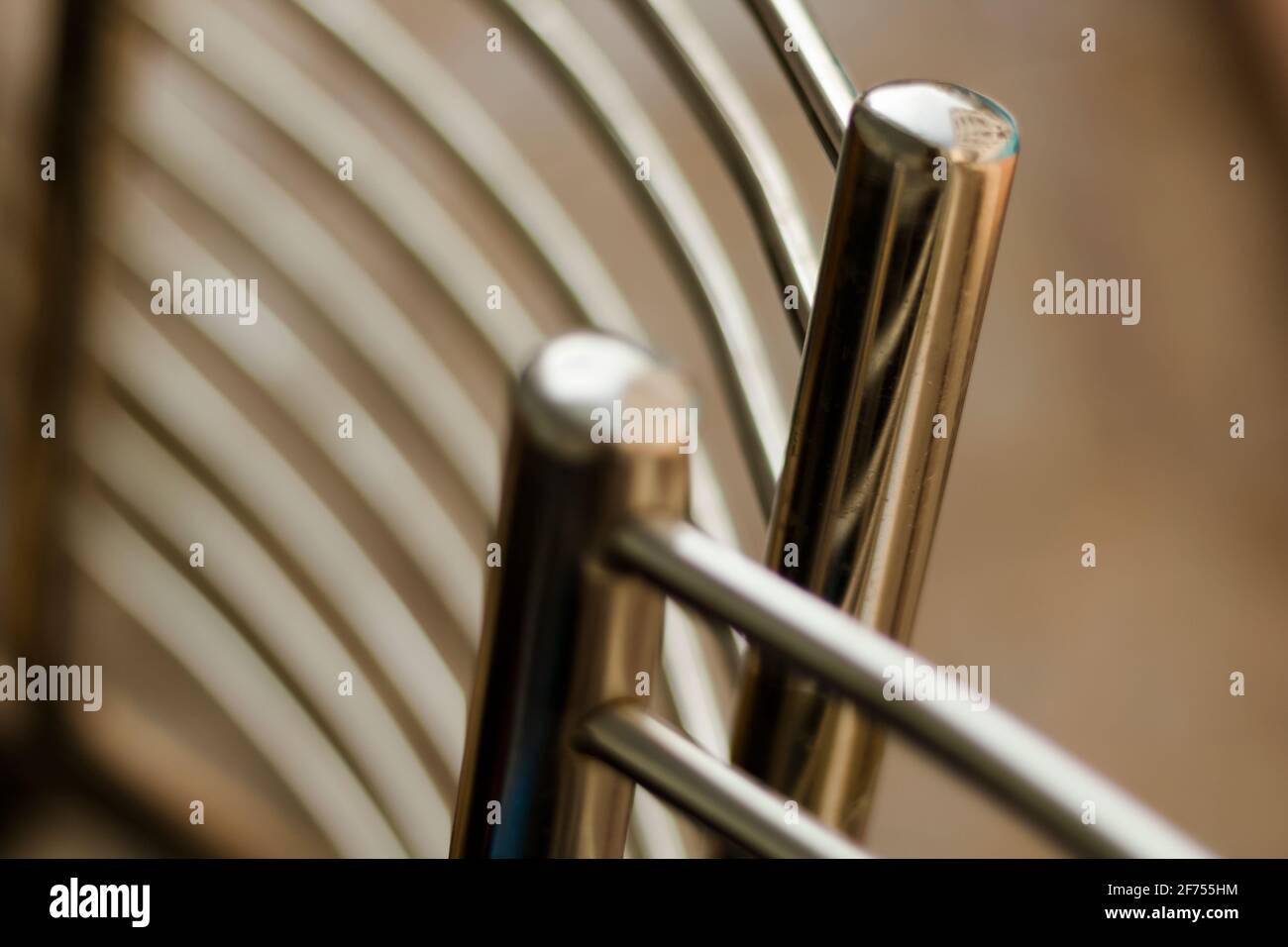 Stainless steel - chrome-nickel. The backs of two garden chairs at the pool. Isolated on brown background. Stock Photo