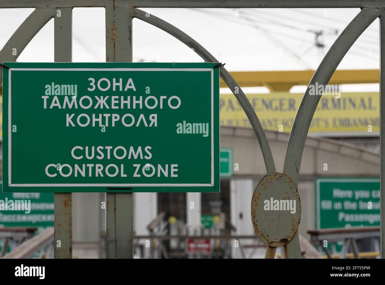 Green sign with the inscription in Russian and English 'Customs control zone' on the grid above the entrance to the customs office (St. Petersburg, Ru Stock Photo