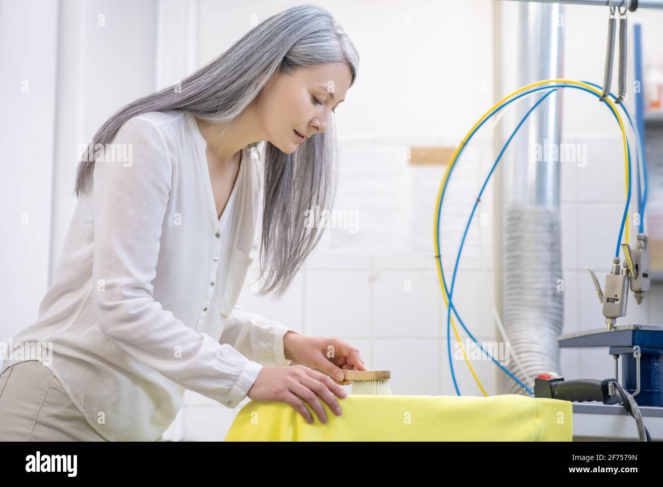 Beautiful adult woman cleaning stain on yellow tshirt Stock Photo